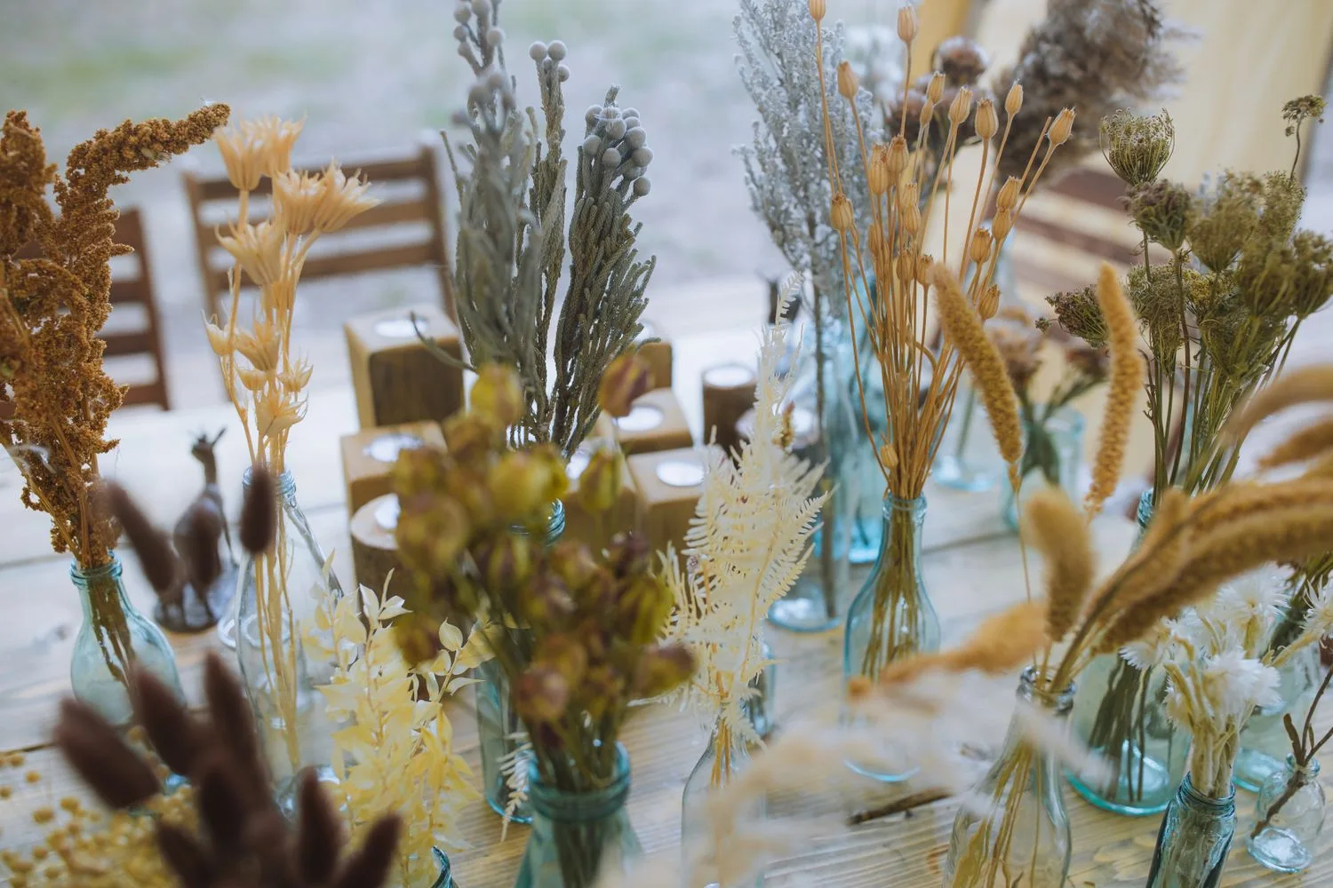 Floral centrepieces and table settings inside an outdoor event tent